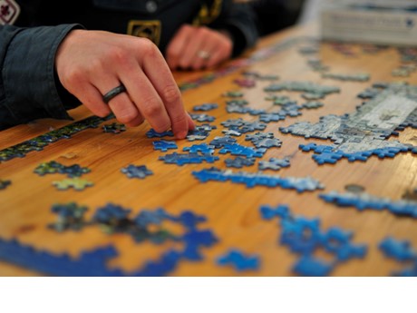Hands putting together a blue colored puzzle