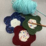photo of three crocheted flower coasters with yarn and crochet hook