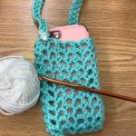 mesh crocheted bag carrying a phone with yarn and crochet hook