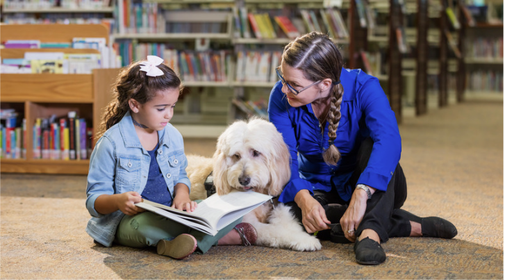 adult, therapy dog, and child reading together