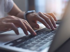 An adult typing on a laptop computer