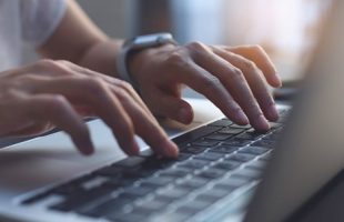 An adult typing on a laptop computer