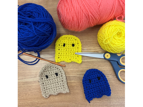various colors of crocheted ghosts with yarn and scissor