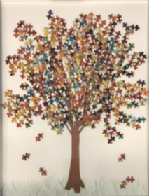A tree, whose leaves are made out of multi colored puzzle pieces.