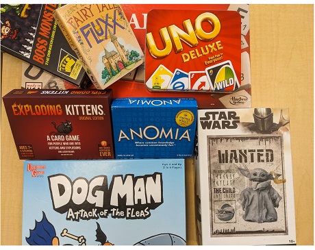 Various board games, card, games and puzzles stacked on a table.