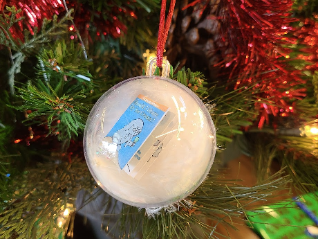 CLear sphere ornament with feather garland and an "elephant and piggie minibook" inside. Backdrop faux christmas tree branches