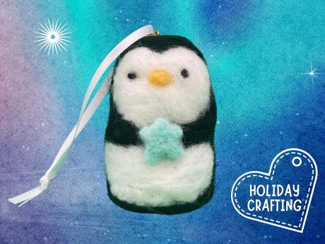 Black and white felted penguin ornament. Penguin is holding a blue star.