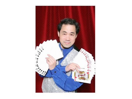 Color front view photo of Magician James Lee holding one hand of large-size playing cards in each hand