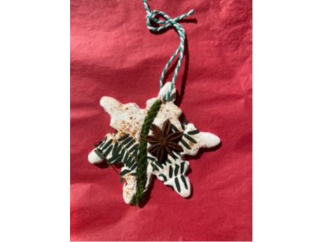 White star shaped ornament decorated with pine cones and leaves