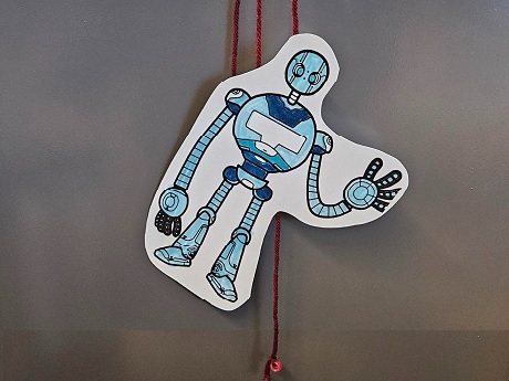 a paper cutout of a robot colored in shades of blue and on a maroon yarn.