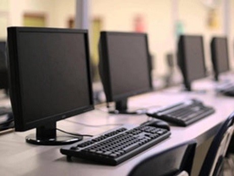 A row of desktop computers on a table.