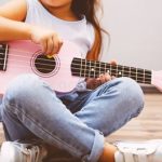 Child playing pink ukulele