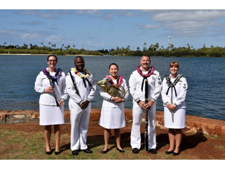 A photo of a woodwind quintet- five individuals dressed in uniform and holding their musical instruments.