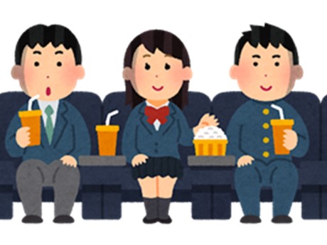 Three students wearing school uniforms watching a movie and eating snacks