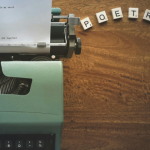 Typewriter with scrabble tiles that spell "POETRY"