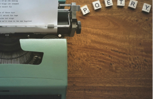 Typewriter with scrabble tiles that spell "POETRY"