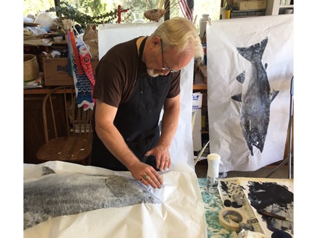 Male artist creating a gyotaku fish print.