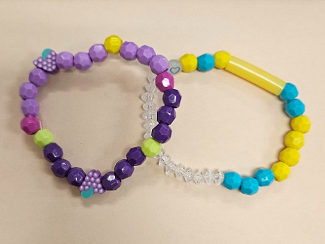 two bead bracelets, one in purple and lavender and one in yellow and mint green