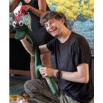 A puppeteer performing with a green snake hand puppet