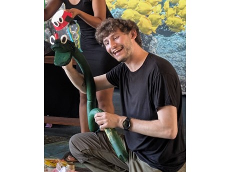 A puppeteer performing with a green snake hand puppet