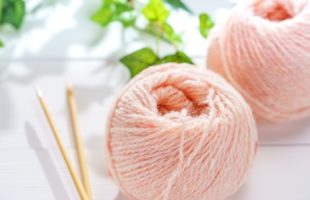 Picture of two pale pink yarn skeins next to craft needles.
