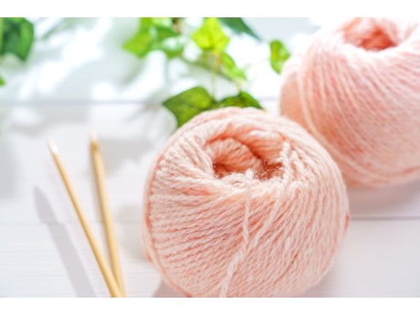 Picture of two pale pink yarn skeins next to craft needles.