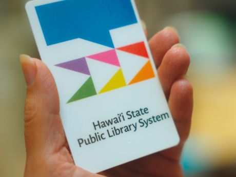 Hand holding a library card with the logo of the Hawaii State Public Library System