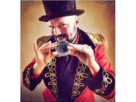 A person in a red jacket and top hat holding a glass ball.