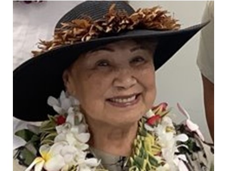A Hawaiian woman wearing a lei and hat with a crown lei