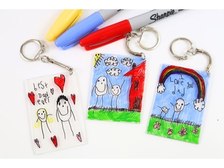 Three keychains featuring colorful children's art and assorted pens.