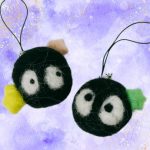 Needle felted soot sprite keychains against a purple background
