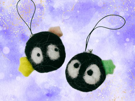 Needle felted soot sprite keychains against a purple background