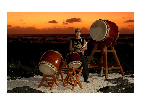 man standing in middle of three taiko drums