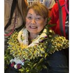 An older woman wearing multiple leis.