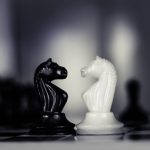 A black and white chess piece facing each other on a chess board