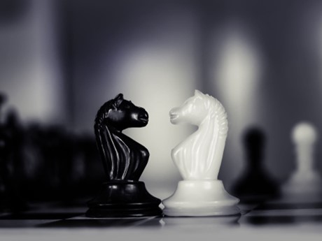 A black and white chess piece facing each other on a chess board