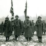 Four soldiers stand with flags