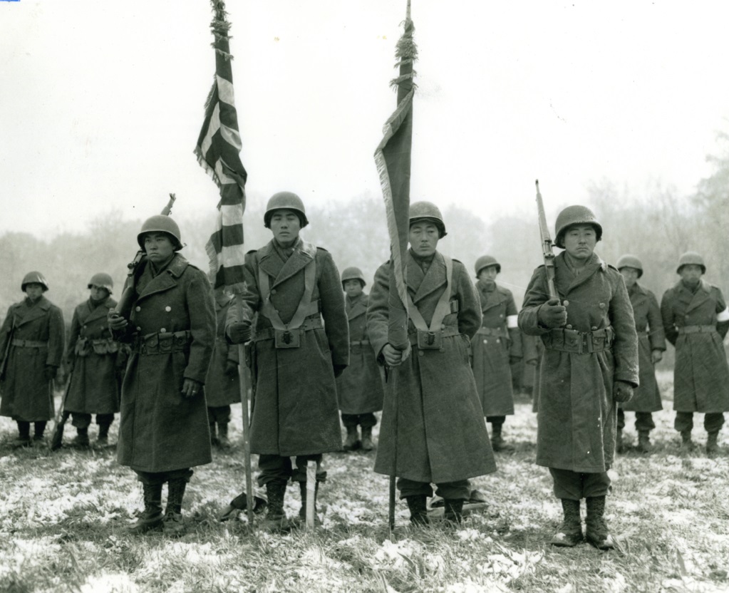 Four soldiers stand with flags