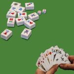 Mahjong pieces and a hand holding cards