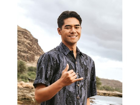 Portrait of a young man wearing an aloha shirt, smiling with shaka.