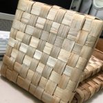 A tan hot pad woven from the lauhala plant.