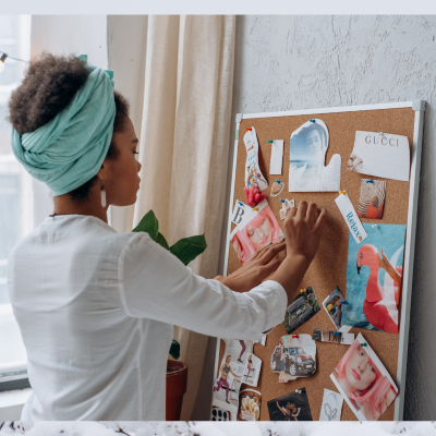 A woman placing pictures on a corkboard.