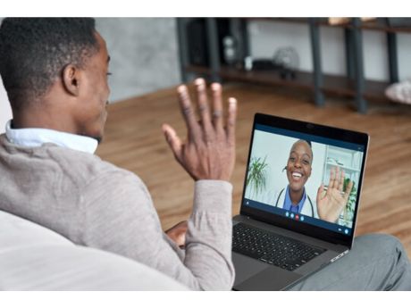 man waving at laptop screen; woman doctor waving on laptop screen