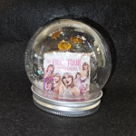a waterless slon gllobe with a mini mock taylor swift book and gems inside, black background