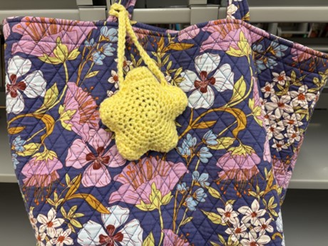 crocheted yellow star acting as tag around floral patterned bag strap