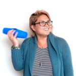 a woman holding two cups taped together, shaking them near her ear