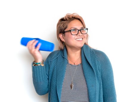 a woman holding two cups taped together, shaking them near her ear