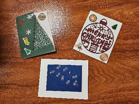 three handmade Christmas cards, a tree, an ornament, and reindeer eyes
