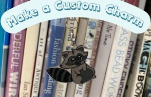 Photo of a racoon design phone charm hanging in front of books. A banner reads "Make a Custom Charm"