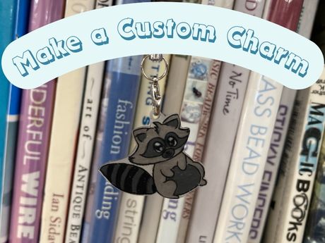 Photo of a racoon design phone charm hanging in front of books. A banner reads "Make a Custom Charm"